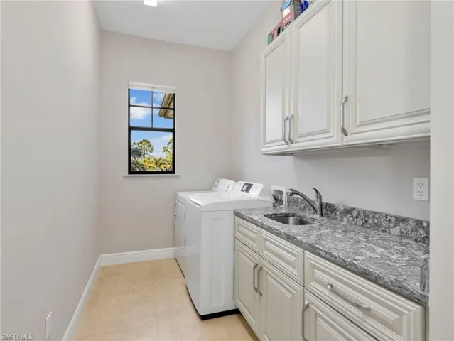 Laundry area with cabinet space, sink, washer/dryer, and tile flooring