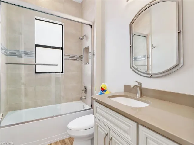upstairs bathroom with vanity, bath / shower combo with glass door