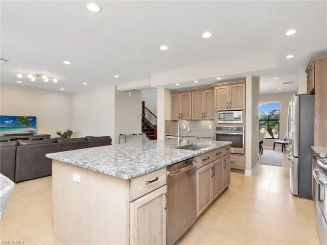 Kitchen featuring open floor plan, GE Profile appliances, light stone countertops, an island with sink, and recessed lighting