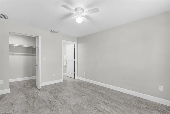 Unfurnished bedroom featuring a walk in closet and ceiling fan