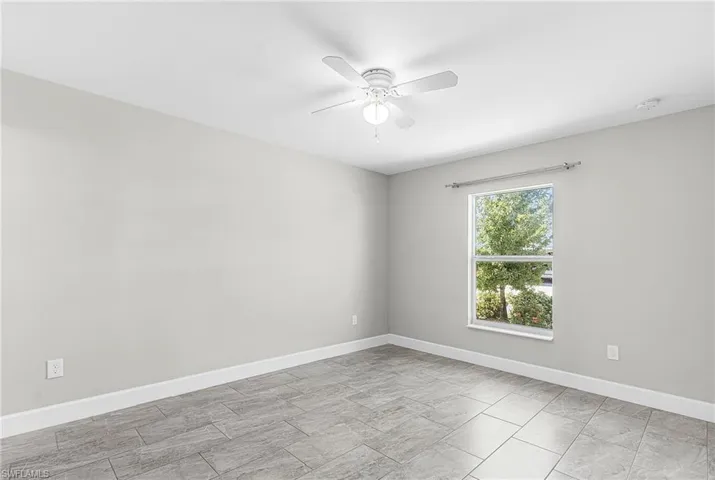 Empty room with baseboards and a ceiling fan