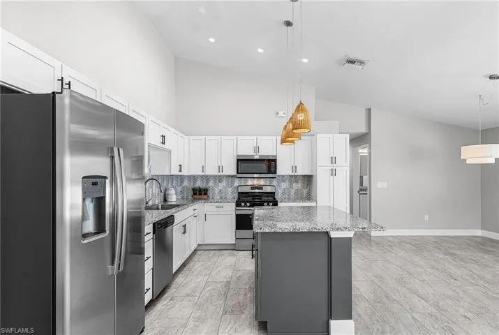 Kitchen featuring appliances with stainless steel finishes, decorative backsplash, white cabinets, pendant lighting, and gray cabinets