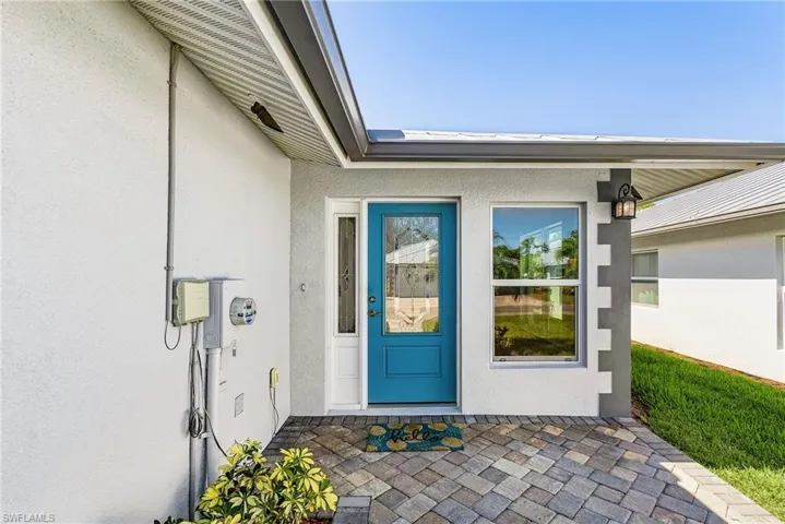 View of exterior entry featuring stucco siding and a patio area