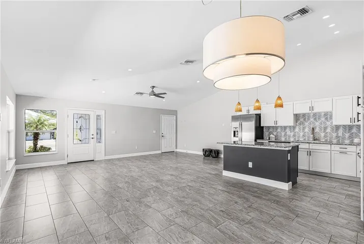 Kitchen featuring white cabinets, pendant lighting, tasteful backsplash, a kitchen island, and a ceiling fan