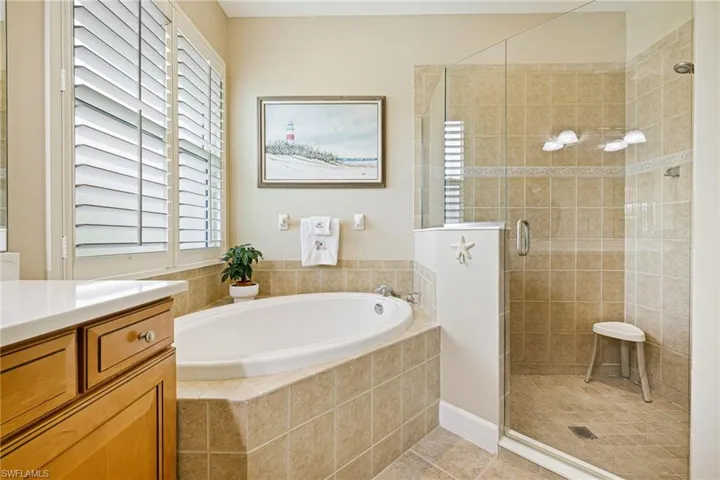 Full bathroom featuring a garden tub, a stall shower, vanity, and healthy amount of natural light
