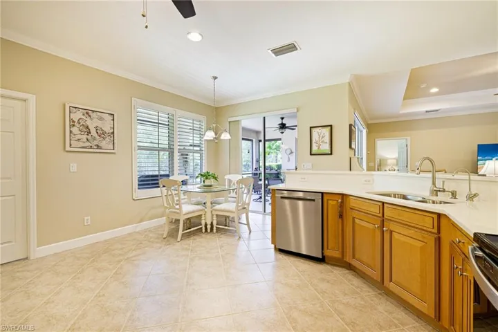 Kitchen featuring dishwasher, ceiling fan, crown molding, brown cabinetry, and light countertops