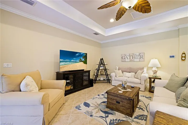 Tiled living room featuring crown molding, a raised ceiling, ceiling fan, and recessed lighting