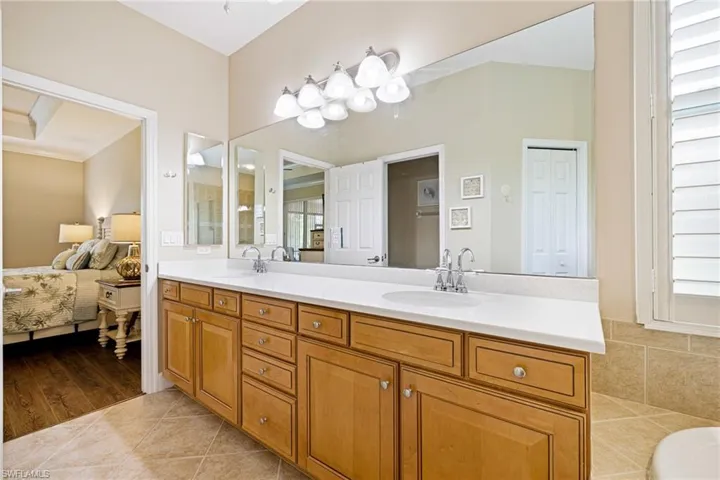 Full bath with double vanity, ensuite bath, a tub to relax in, and crown molding