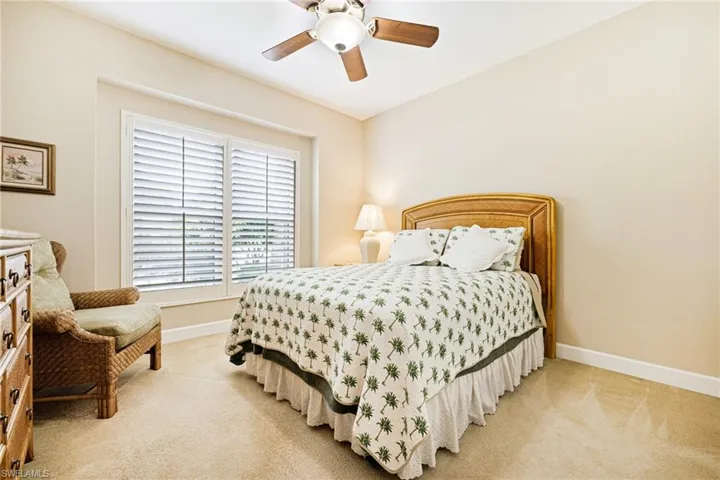 Bedroom with light colored carpet and a ceiling fan