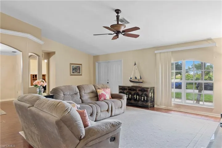Living room with lofted ceiling, ceiling fan, and wood-type flooring