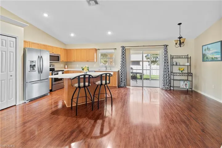 Kitchen with a center island, vaulted ceiling, stainless steel appliances, dark wood-type flooring, and a kitchen bar