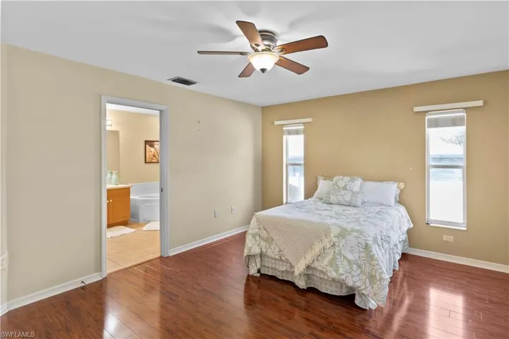 Bedroom featuring ceiling fan, wood-type flooring, and ensuite bathroom
