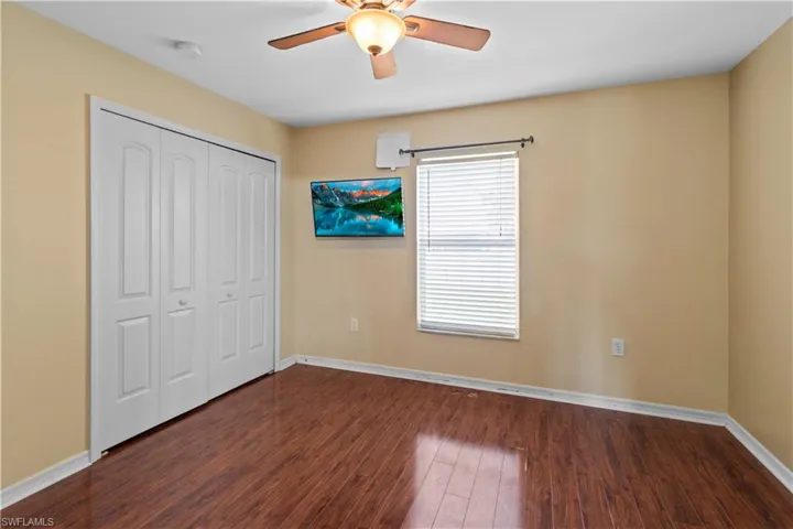 Unfurnished bedroom with dark wood-type flooring, a closet, and ceiling fan