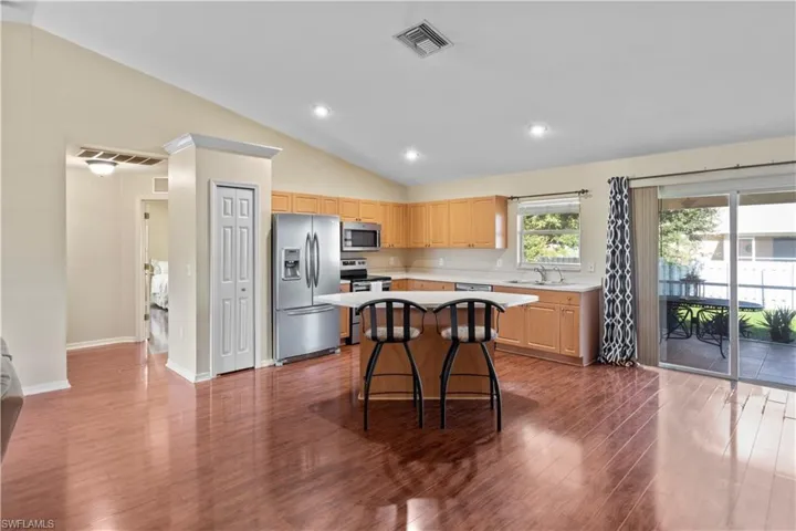Kitchen with stainless steel appliances, a kitchen breakfast bar, dark hardwood / wood-style flooring, a kitchen island, and sink