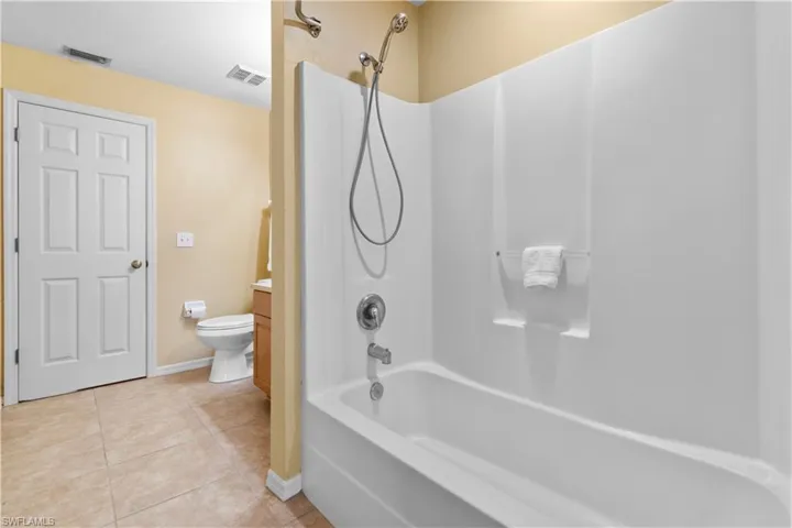 Full bathroom featuring tile patterned flooring, vanity, toilet, and washtub / shower combination