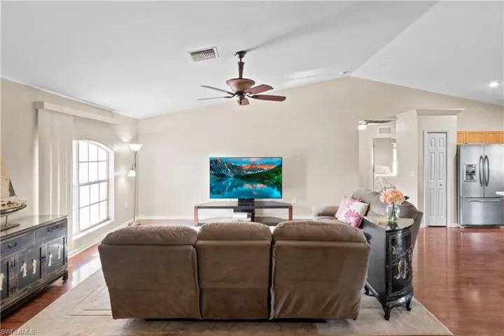 Living room featuring ceiling fan, dark hardwood / wood-style floors, and vaulted ceiling