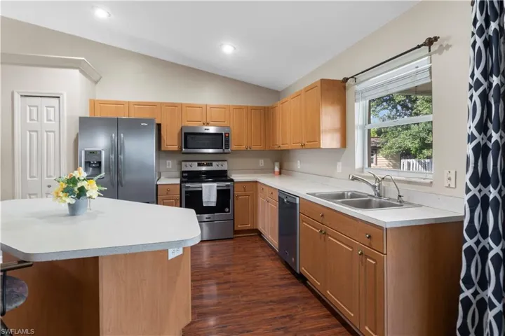 Kitchen with lofted ceiling, sink, appliances with stainless steel finishes, and dark hardwood / wood-style flooring