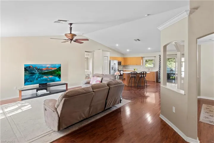 Living room with lofted ceiling, ceiling fan, and dark hardwood / wood-style floors