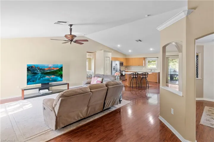 Living room featuring dark wood-type flooring, ceiling fan, and high vaulted ceiling