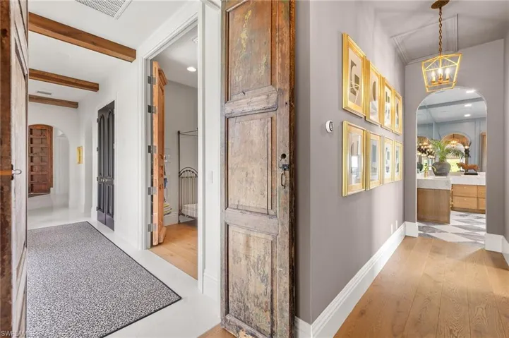 Corridor featuring arched walkways, visible vents, a chandelier, and light wood-style floors