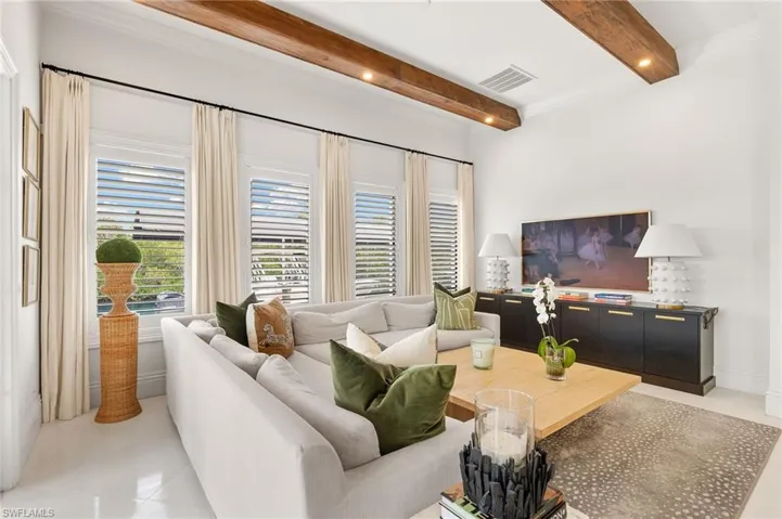 Living area featuring beam ceiling, light tile patterned flooring, and visible vents