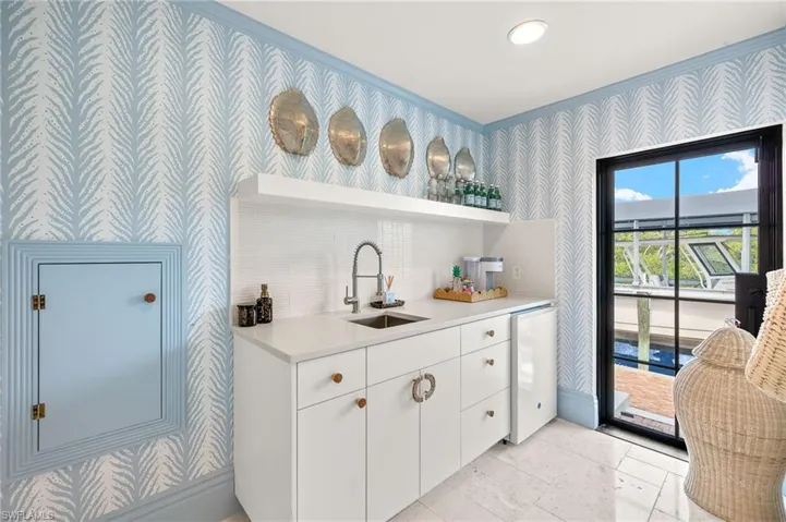 Bar with a sink, crown molding, wet bar, refrigerator, and wallpapered walls