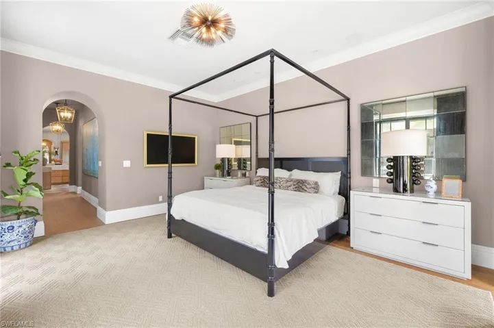Bedroom with ornamental molding, light wood-type flooring, arched walkways, and baseboards