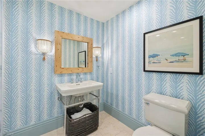 Half bath featuring toilet, a sink, wallpapered walls, and baseboards