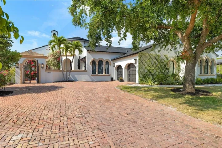 Mediterranean / spanish home featuring a chimney, a gate, decorative driveway, an attached garage, and stucco siding