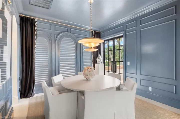 Dining space with crown molding, visible vents, and a decorative wall