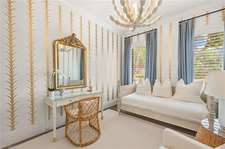 Sitting room featuring a chandelier, a wealth of natural light, crown molding, baseboards, and wallpapered walls