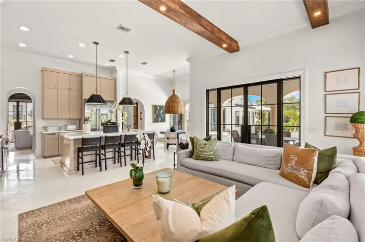 Living area with recessed lighting, arched walkways, beam ceiling, visible vents, and crown molding
