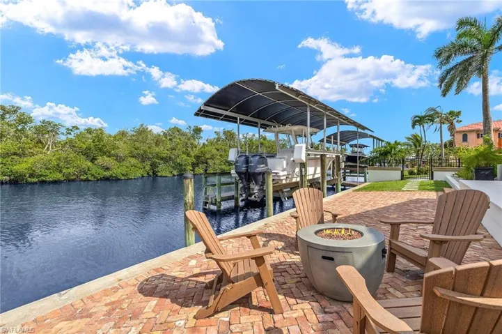 Dock area featuring boat lift, a fire pit, and a water view