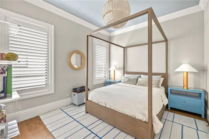 Bedroom with ornamental molding, wood finished floors, and baseboards