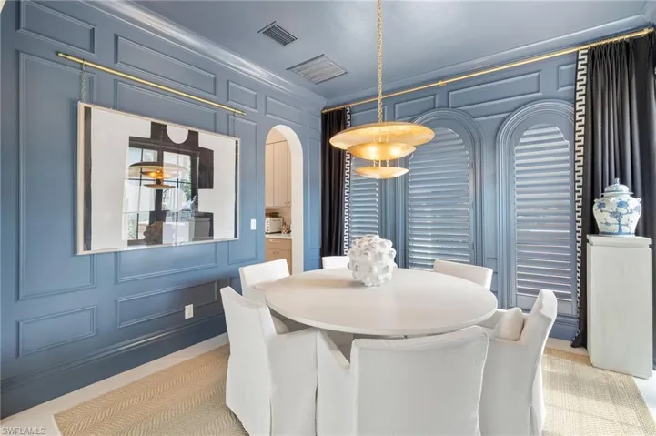Dining area with a decorative wall, visible vents, and arched walkways