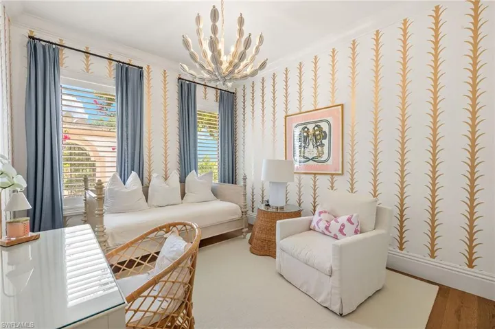 Sitting room with wallpapered walls, a wealth of natural light, a chandelier, and baseboards