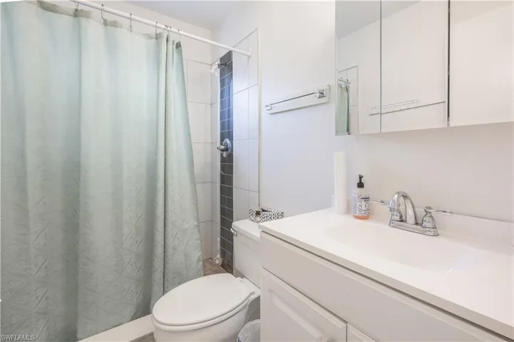 Bathroom with vanity, a shower with shower curtain, and toilet