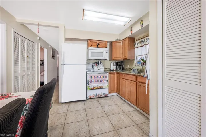 Kitchen featuring backsplash, light stone countertops, sink, and white appliances
