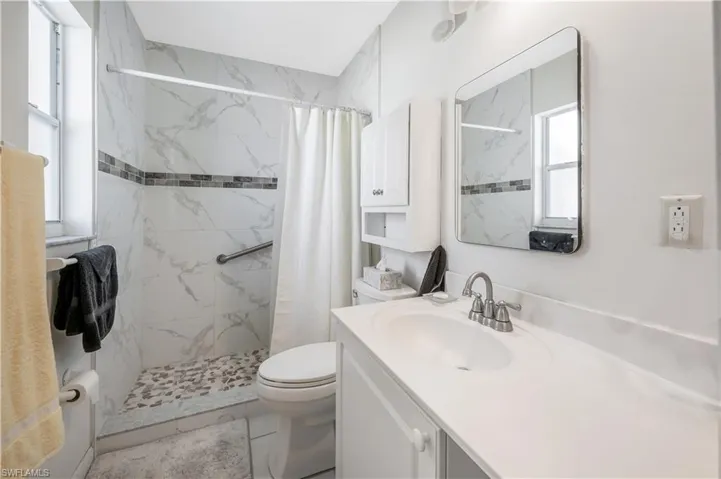 Bathroom featuring a shower with shower curtain, tile patterned floors, vanity, and toilet