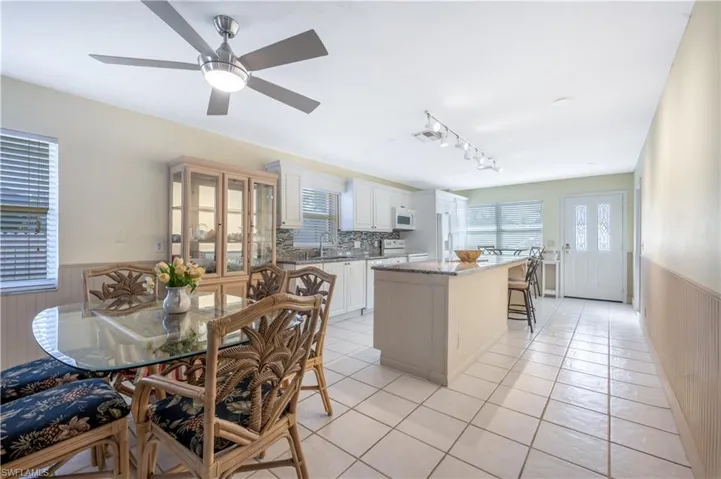 Kitchen with white appliances, rail lighting, sink, a kitchen island, and white cabinetry