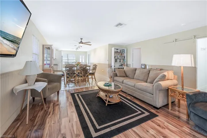 Living room with ceiling fan, wood-type flooring, and wood walls