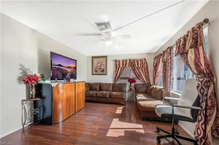 Living room with ceiling fan, dark hardwood / wood-style floors, and a textured ceiling