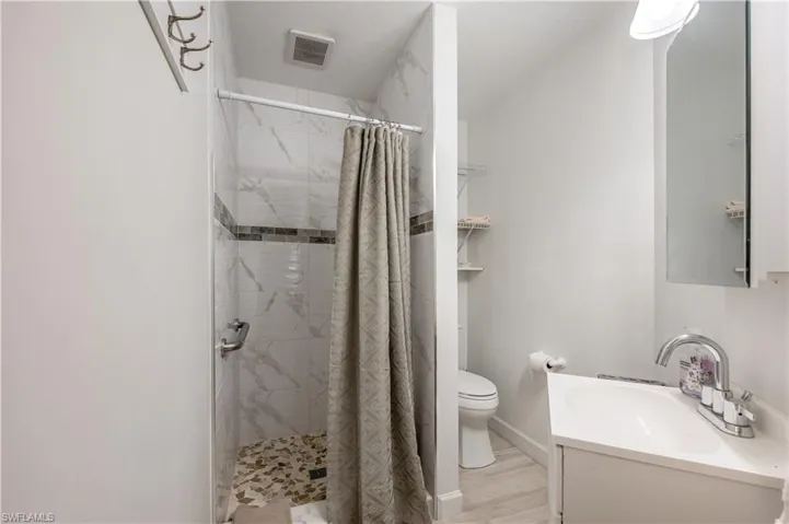 Bathroom featuring vanity, curtained shower, and toilet