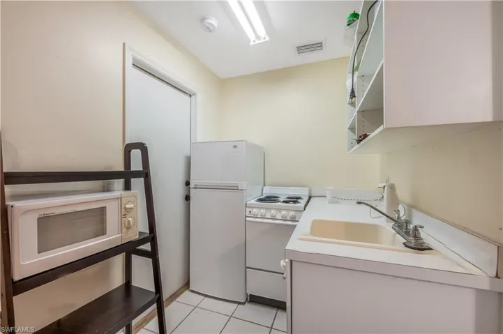 Kitchen with light tile patterned floors, white appliances, and sink