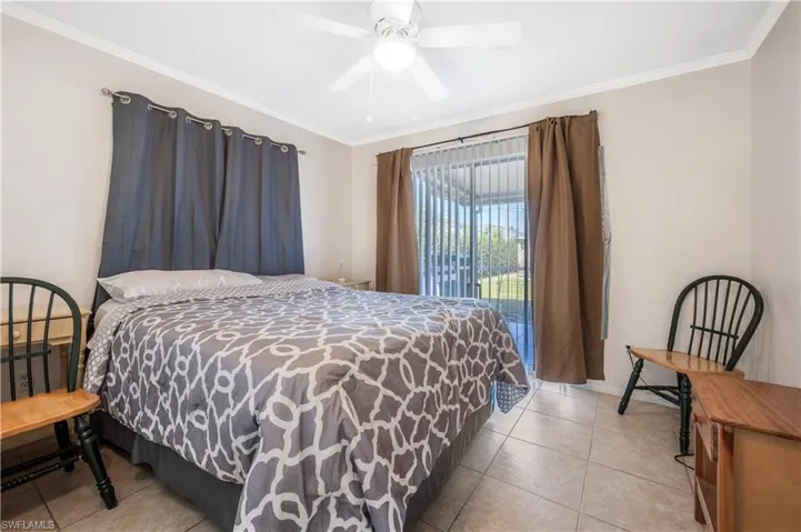 Bedroom featuring access to exterior, ceiling fan, light tile patterned floors, and ornamental molding