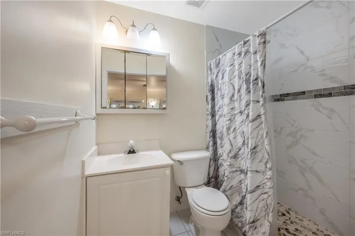 Bathroom featuring tile patterned flooring, vanity, toilet, and walk in shower