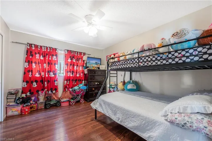 Bedroom featuring ceiling fan, dark hardwood / wood-style flooring, and a textured ceiling