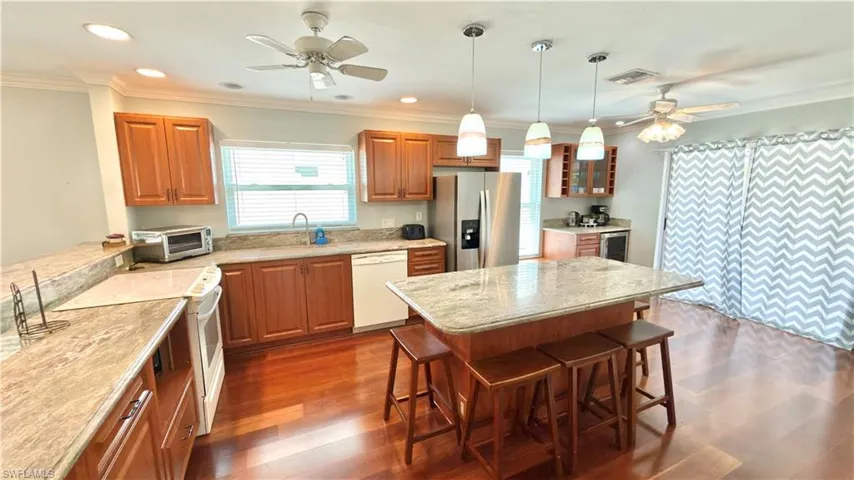 Kitchen featuring wood-finish flooring, recessed lighting, a kitchen island with pendant lighting, wood cabinetry.