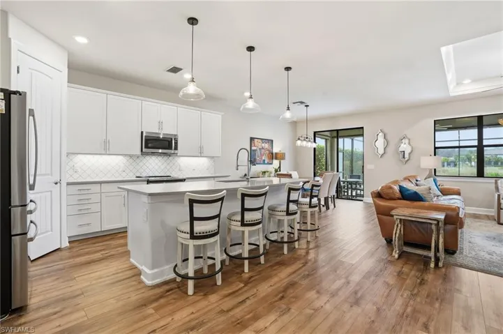 Kitchen featuring a breakfast bar area, pendant lighting, white cabinetry, a center island with sink, and recessed lighting