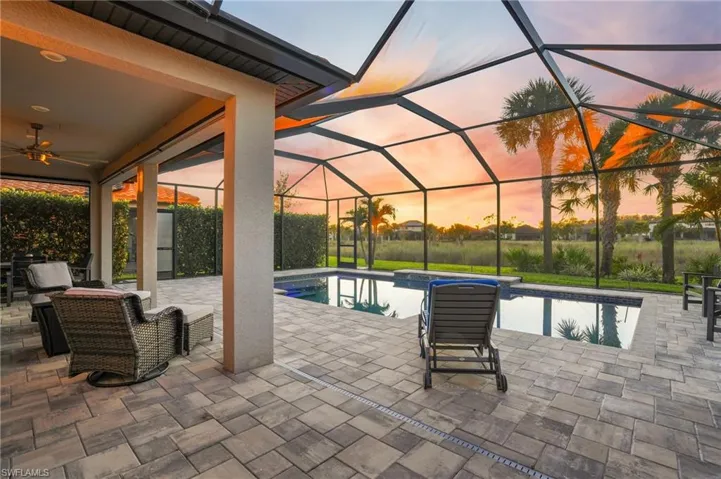 Pool at dusk with an outdoor pool, a patio, a lanai, and a sunroom